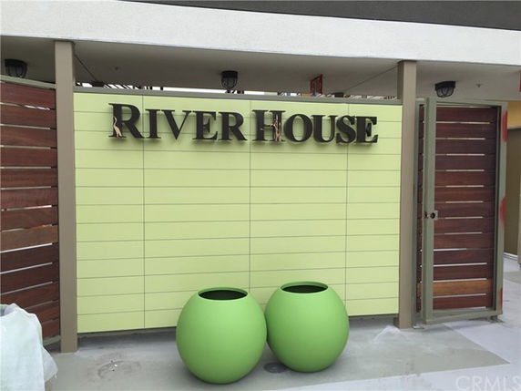Entrance view of a building with a sign reading 'River House' and two green pots.