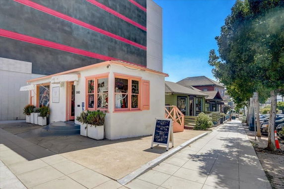 Front view of a small shop building on a sidewalk with adjacent structures.