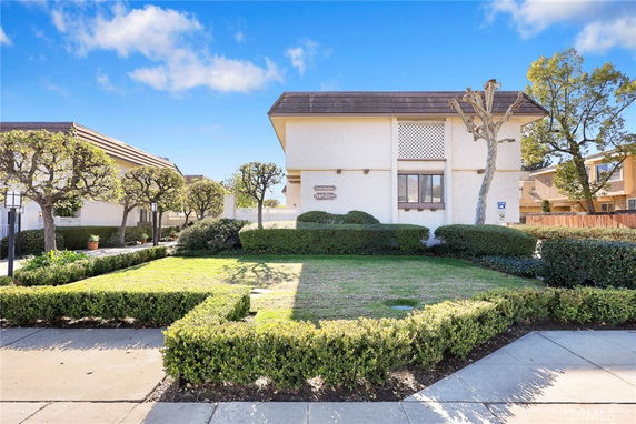 Front view of a two-story house with a flat roof and well-maintained garden.
