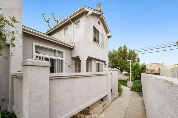 Front view of a two-story house with multiple satellite dishes on the roof.