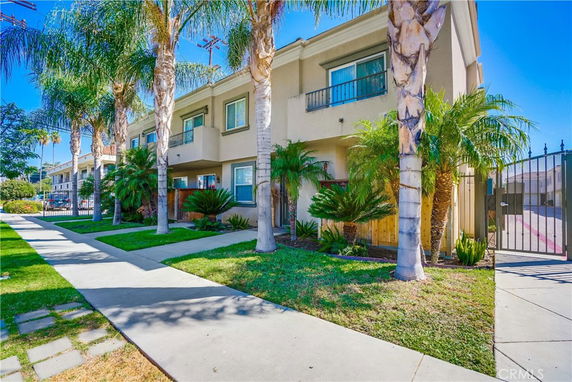 Front view of a two-story apartment building with palm trees in front.