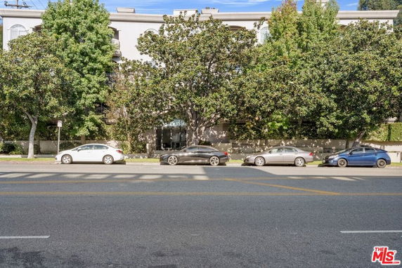 Front view of a multi-story building partially obscured by tall trees.