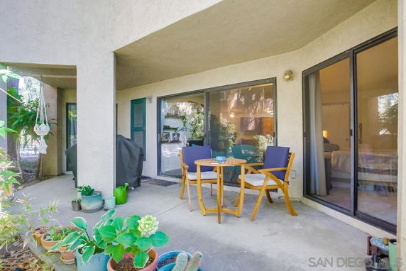 Patio area with outdoor seating next to a building with sliding glass doors.