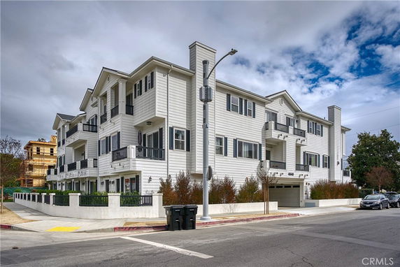Front view of a three-story apartment building with multiple balconies and garages.