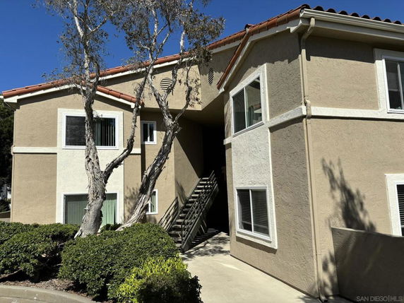 Front view of a two-story residential building with multiple windows and an exterior staircase.