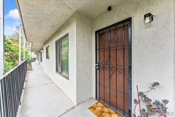 Exterior view of an apartment hallway with windows and a metal security door.