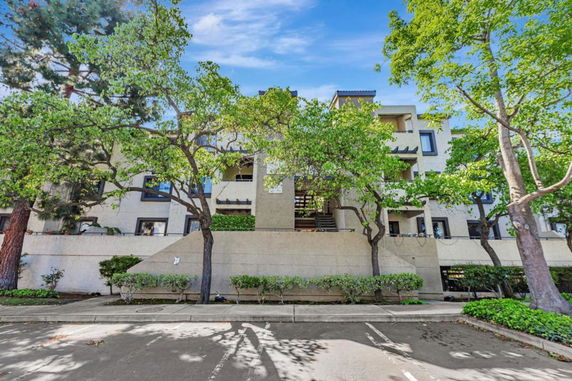 Front view of a multi-story residential building with trees in front.