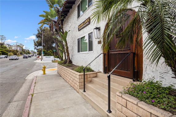 Front view of a condominium building entrance with a wooden door and steps.
