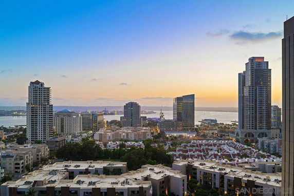 Panoramic view of a cityscape with high-rise buildings and a body of water at sunset.