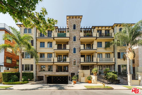 Front view of a multi-story residential building with a stone facade and balconies.