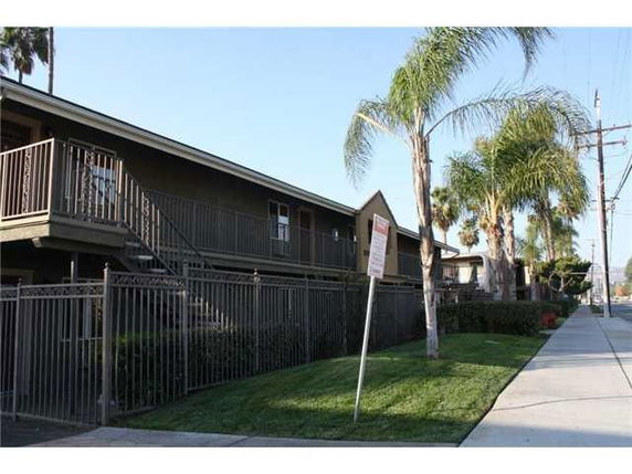Front view of a two-story apartment building with stairs and railing.
