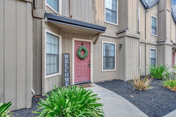 Front view of a multi-story house with a red door and welcome sign.