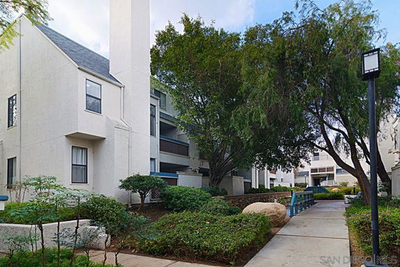 Front view of a multi-story residential building with a chimney and surrounding greenery.