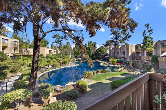 View of apartment buildings surrounding a landscaped garden with a pond.