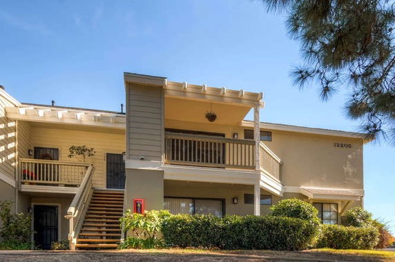 Front view of a two-story residential building with balconies and stairs.