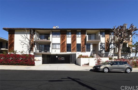 Front view of a multi-story residential building with a gated entrance and balconies.