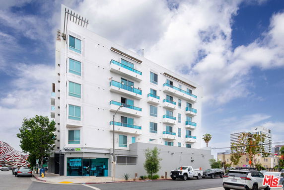 Front view of a multi-story building with balconies and a ground floor spa.