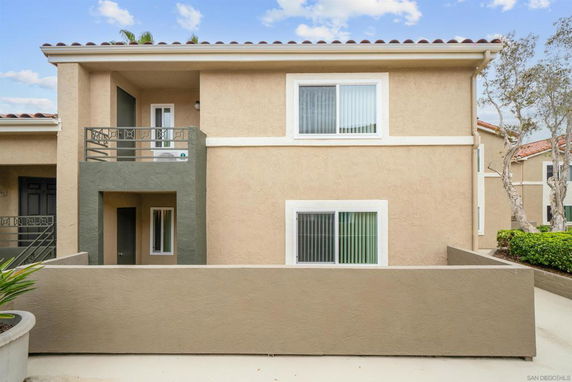 Front view of a two-story house with a small balcony and beige exterior walls.