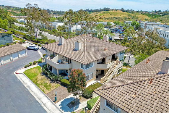 Aerial view of a two-story building with a tile roof and surrounding landscape.