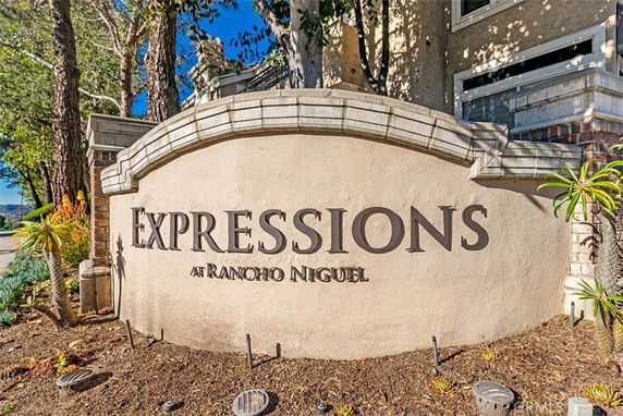 Entrance view of a housing community with a stone sign reading 'Expressions at Rancho Niguel'.