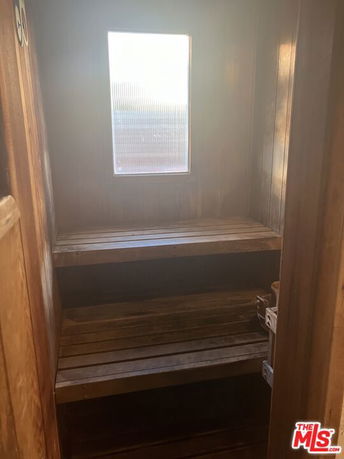 Interior view of a wooden sauna with benches and a window.
