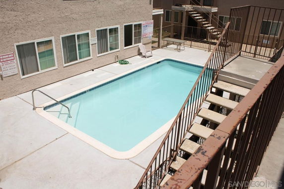 Outdoor swimming pool area with surrounding building.