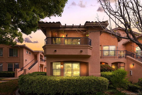 Front view of a two-story house with balconies and stairs.