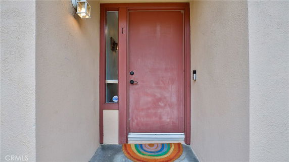 Front view of a house entrance with a red door and a side window.