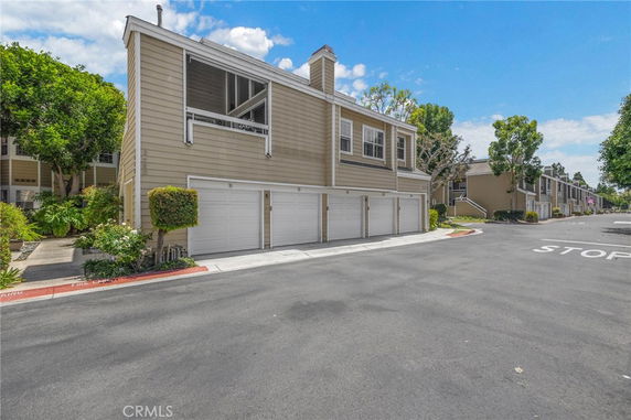 View of a beige multi-unit residential building with garages on the ground level.