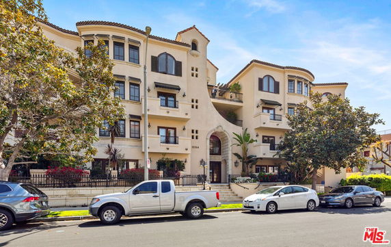 Front view of a multi-story residential building with balconies and arched windows.