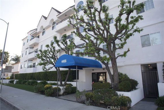 Front view of a multi-story apartment building with a blue awning entrance.