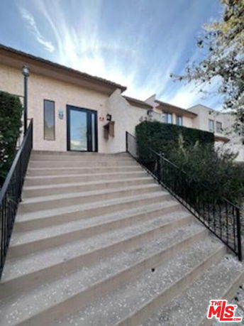 Front view of a building with a staircase leading to the entrance.