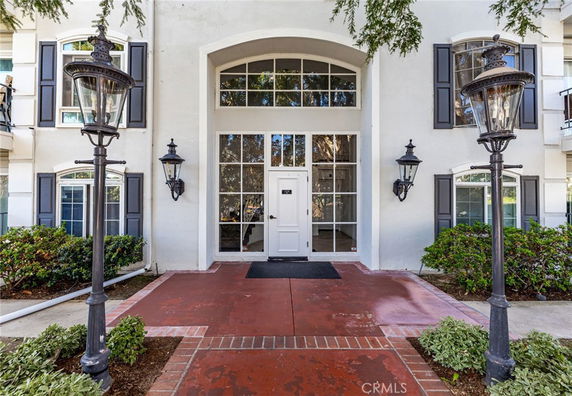 Front view of a building entrance with large windows and decorative lamps.