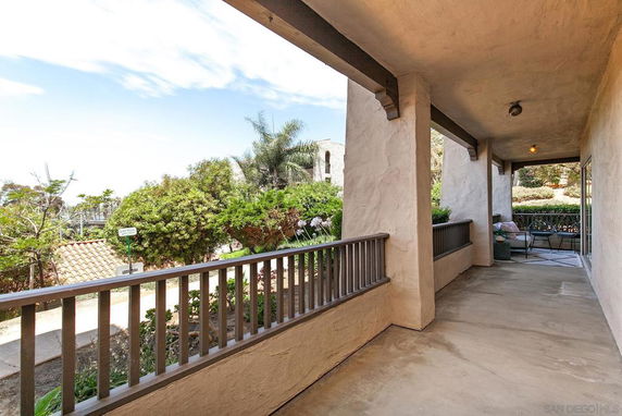 Patio view with railing and greenery outside a house.