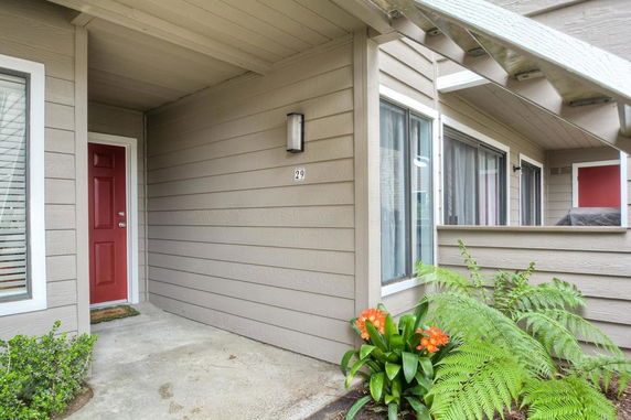 Front view of a house with a red door and gray siding.