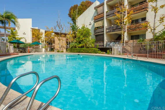 Outdoor swimming pool area with residential buildings in the background.