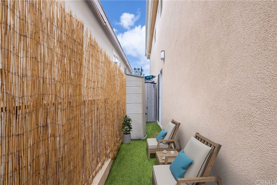 Narrow outdoor space with chairs and bamboo fencing.