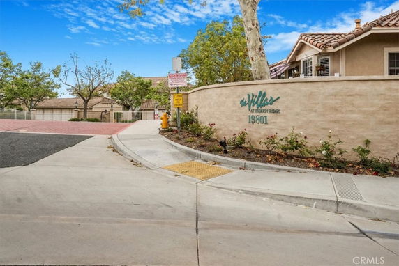 Entrance view of a gated community with a sign reading 'The Villas at Hidden Ridge' on a wall.