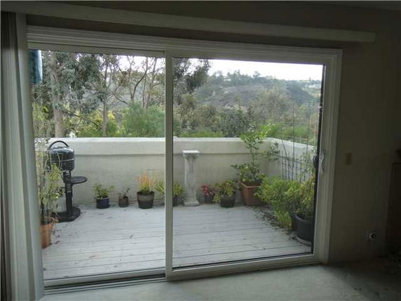 View of a balcony with potted plants and a distant view of hills.