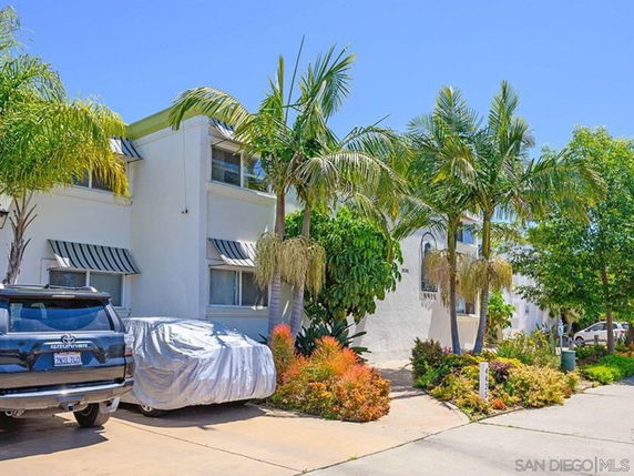 Front view of a two-story house with palm trees and driveway.