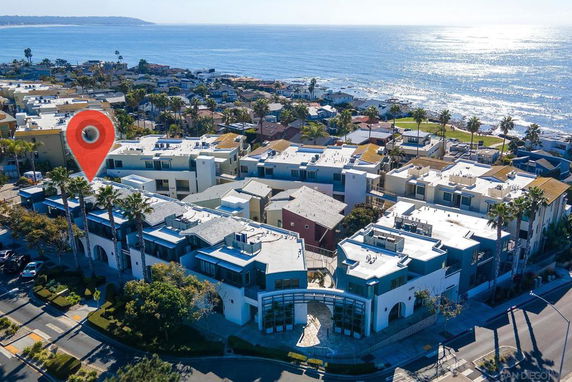 Panoramic view of coastal residential area with a large white building complex and the ocean in the background.