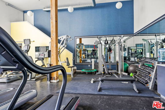 Interior view of a gym with exercise equipment including treadmills, weights, and a weight machine.