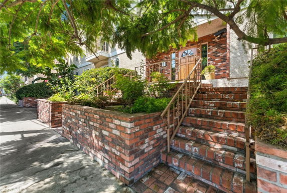 Front view of a house with a brick staircase and surrounding greenery.