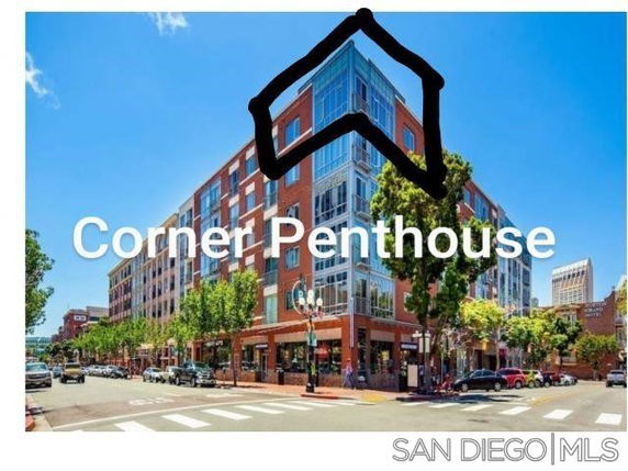 Front view of a multi-story building with ground-level shops and corner penthouse.