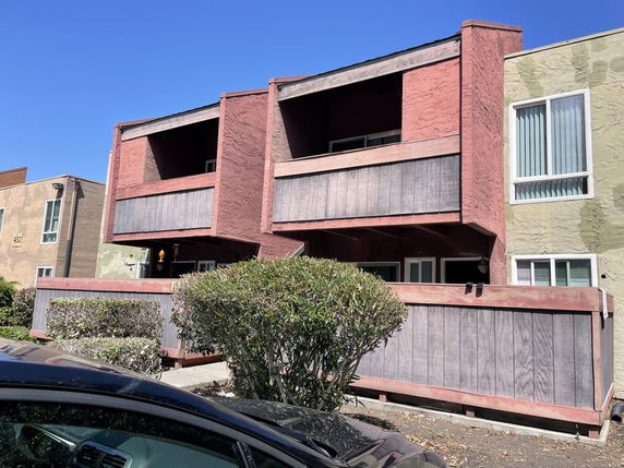 Front view of a two-story building with a balcony and fence.