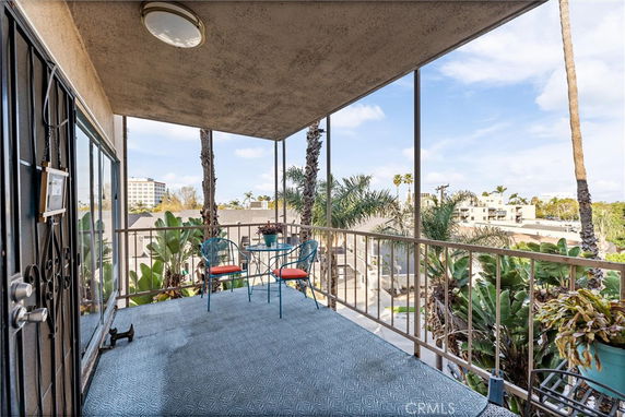 View from a balcony overlooking a cityscape with palm trees and buildings.