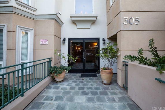 Front view of a building entrance with double glass doors and potted plants.