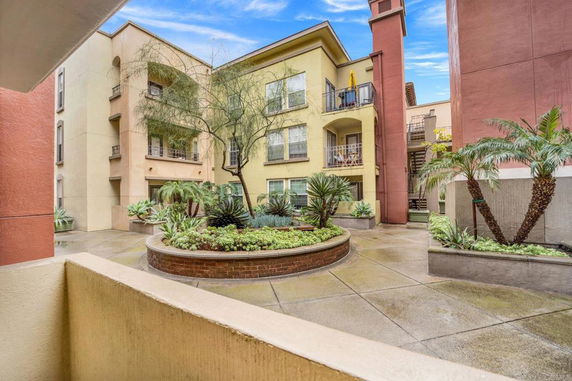 Courtyard view of a multi-story residential building with balconies and landscaped garden.