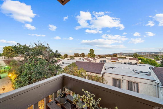 Panoramic view of residential rooftops and surrounding landscape from a balcony.