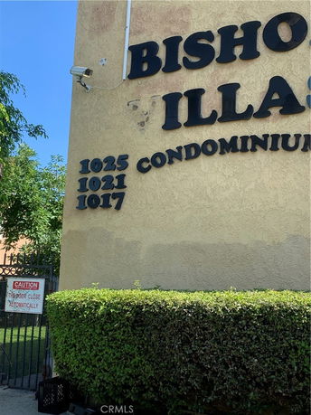 Front view of a condominium building with visible signage and a gated entrance.